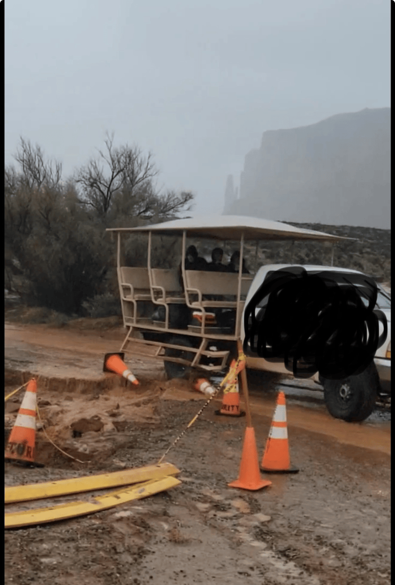 Open vehicle stuck in muddy road with traffic cones around